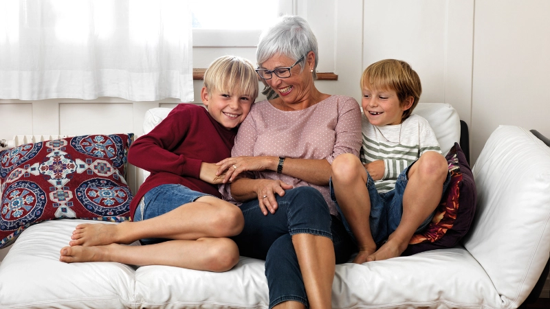 Seniorin mit Enkeln auf dem Sofa, Seniorin im Klassenzimmer