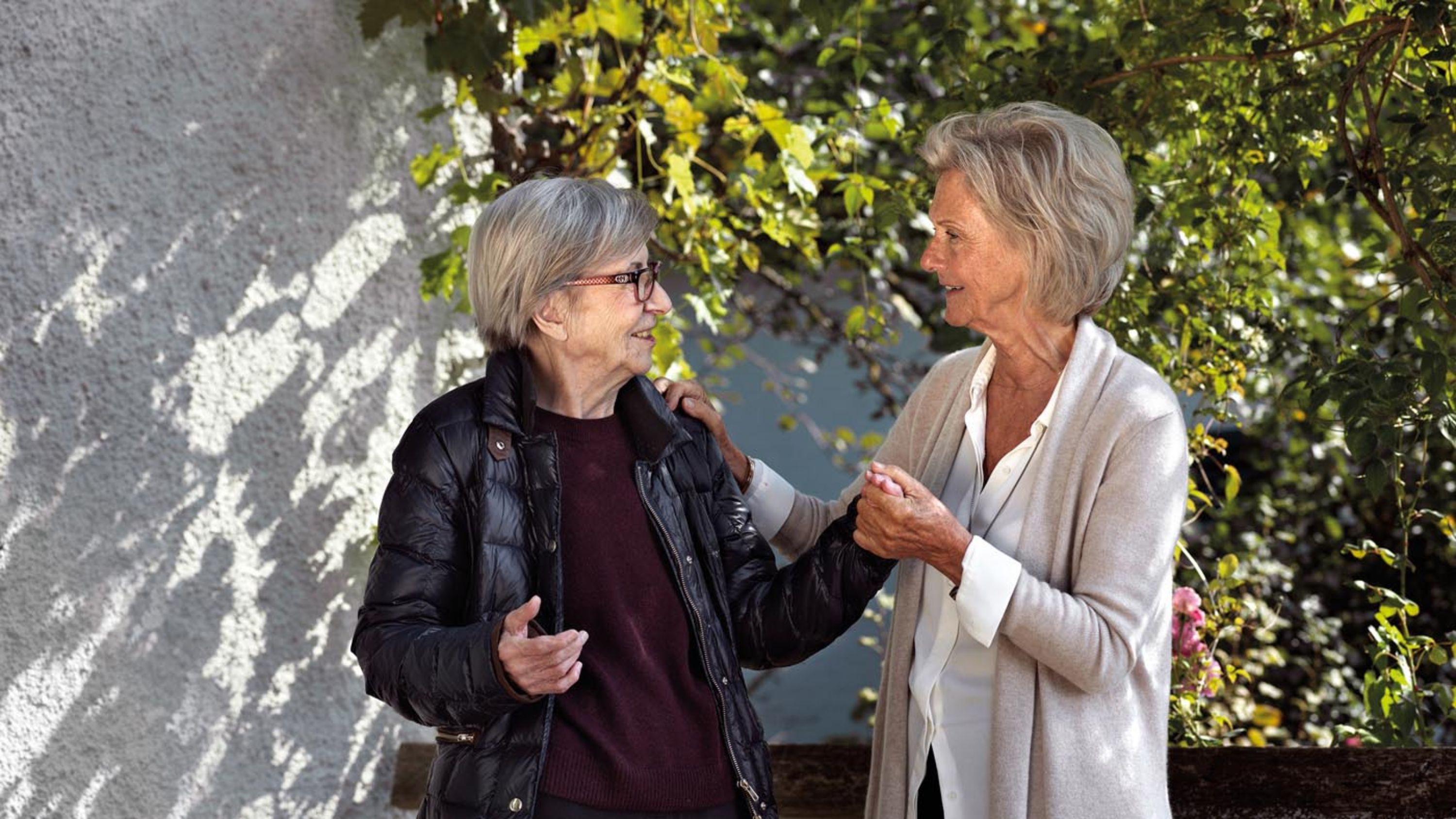 Deux femmes âgées discutent entre elles et se tiennent par la main.