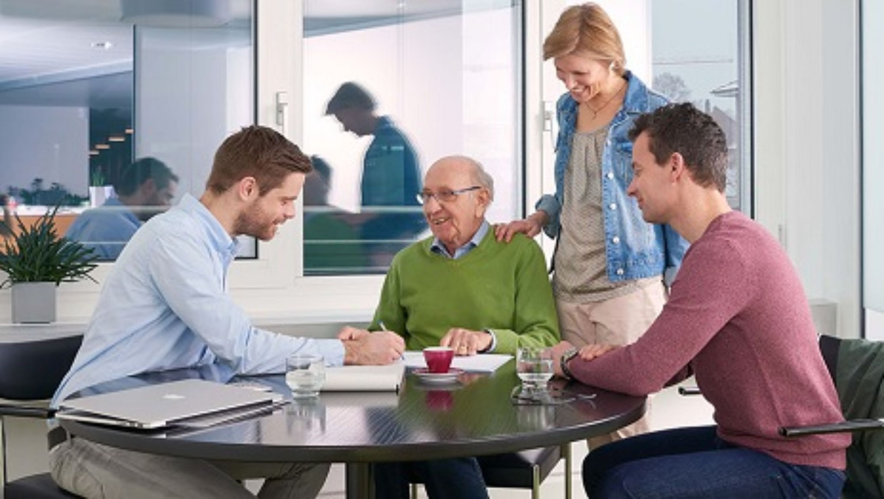 Menschen um einen Tisch sitzend und stehend